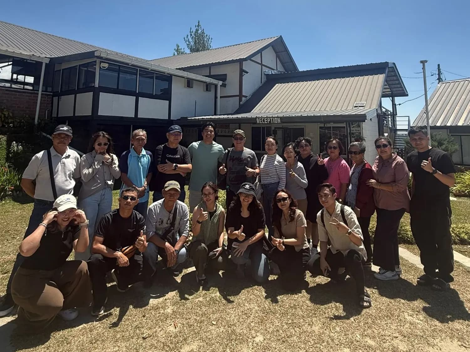 A family group posing on the lawn outside reception at The Hill Kinabalu on a sunny day